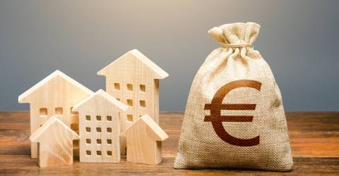 Houten huisjes met een zak met geld waarop een euro teken staat